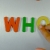 Hand Writes Who with Fridge Magnets Close-Up