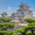 Himeji Castle, a hilltop Japanese castle by the city of Himeji, Hyōgo Prefecture, Japan. With trees in foreground.