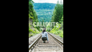 Girl on straight railroad tracks through dense forest